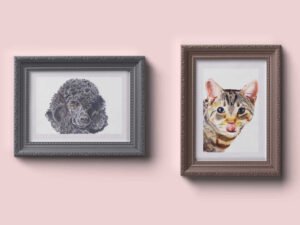 Framed paintings of a black poodle and a brown tabby cat hung on a pink wall