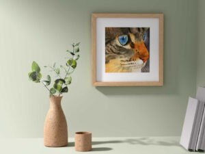 A framed portrait of a cat hangs on the wall beside a decorative vase, creating an elegant home decor scene.